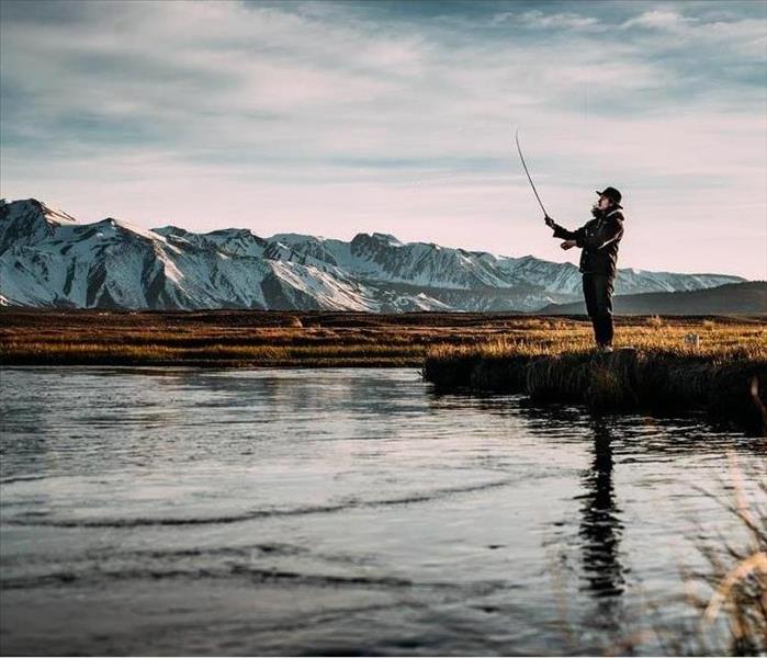man fishing with beautiful mountains in the background