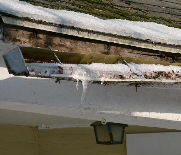 gutters on a home full of ice and leaves