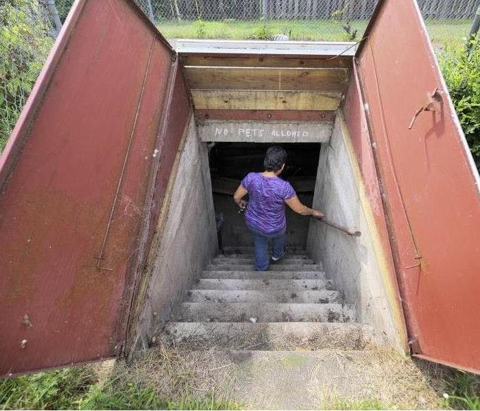 underground storm shelter with a woman going downstairs
