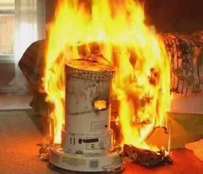 space heater on fire in front of a bed