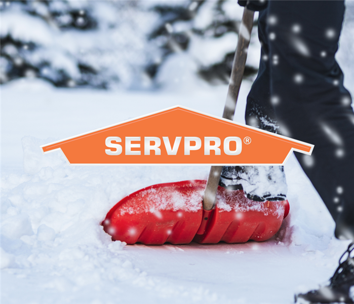 someone shoveling thick snow with the SERVPRO logo on top of the photo 